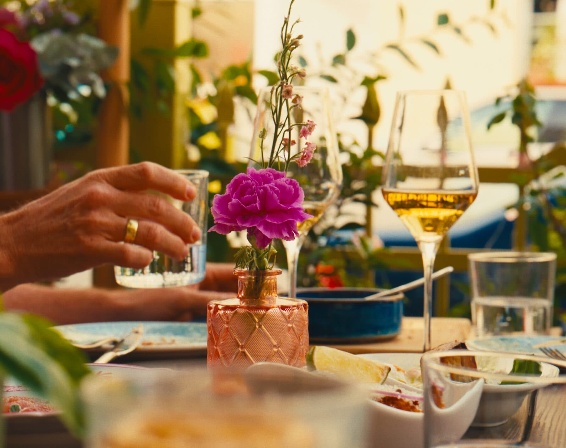 Glas Weißwein auf dem Tisch, daneben eine Blüte